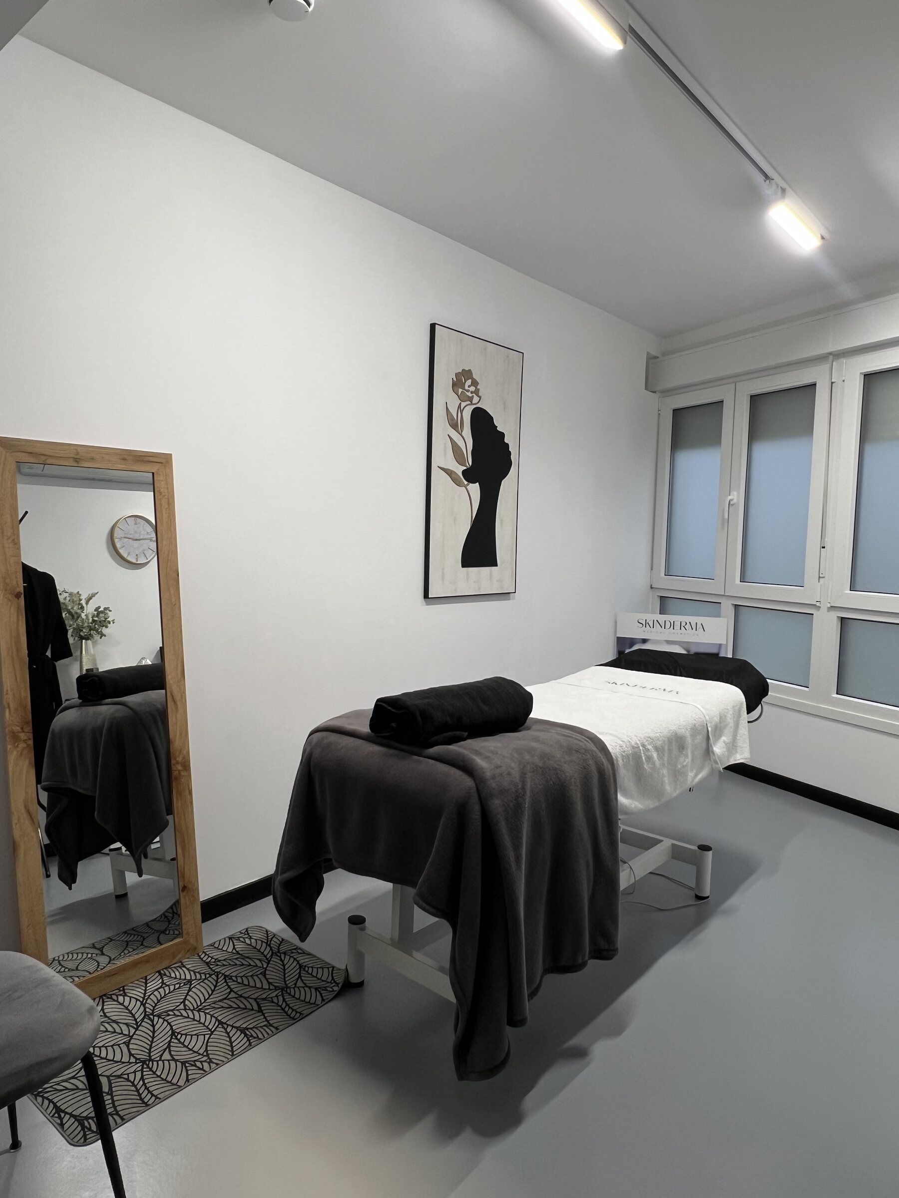 Cabina de estética con camilla, espejo de pie y cuadro decorativo